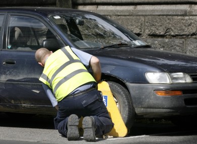 A clamper attaches a clamp in Dublin city.