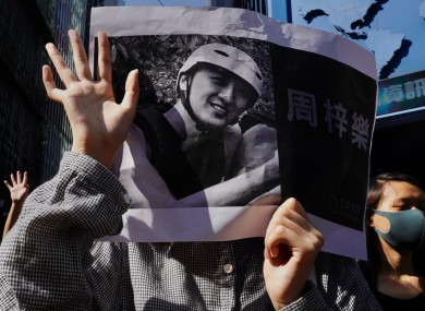 Protesters hold a photo of Alex Chow who died
