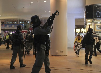 Police in Hong Kong point guns at protesters in a shopping centre.