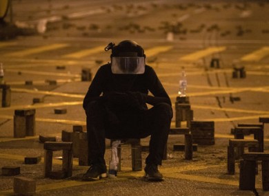 A protester sits with brick obstacles and Molotov cocktail on a barricade road near the Hong Kong Polytechnic University.