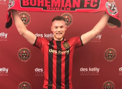 Kelly. in the Gypsies home shirt, holds up a club scarf.