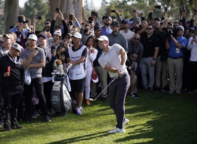 Rory McIlroy watches his second shot while surrounded by spectators on the 18th hole during the third round of the Genesis Invitational golf tournament at Riviera.