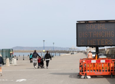 People walking on a sunny Dun Laoghaire pier last week reminded of social distancing.