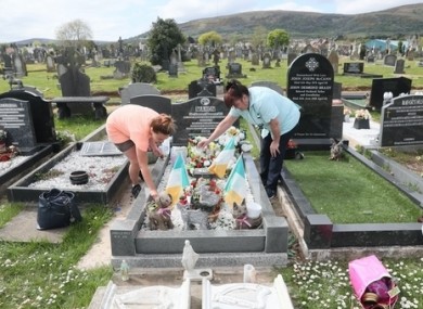 Two women water plants at Milltown Cemetery in Belfast.