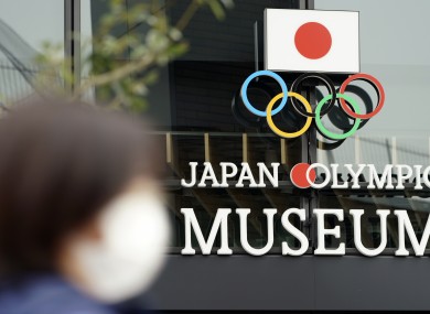 A woman wearing a mask against the spread of Covid-19 walks in front of the Japan Olympic Museum building in Tokyo.