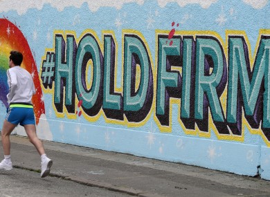 A man runs past a new mural in Dublin's city centre inspired by the new HSE 'Hold Firm' campaign - which took its inspiration from a poem by President of Ireland Michael D Higgins.