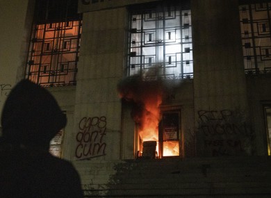A protester watches as a mall fire burns in the entrance of the Alameda County Courthouse