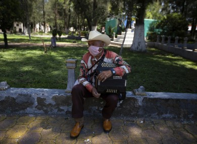 A musician waits for clients to hire him to serenade mourners during burial services on the outskirts of Mexico City.