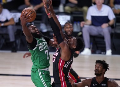 Boston Celtics' Jaylen Brown goes up for a shot as Miami Heat's Bam Adebayo and Jimmy Butler defend.