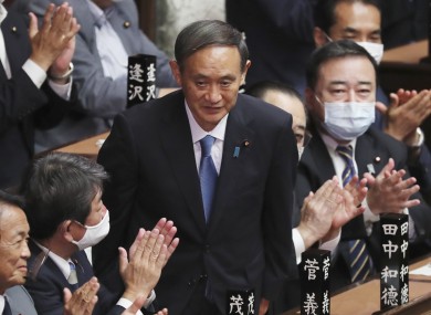 Yoshihide Suga stands up after being elected as Japan's new prime minister today.