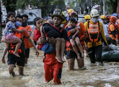 Rescuers carry children out from a flooded street due to heavy rains brought by Typhoon Vamco