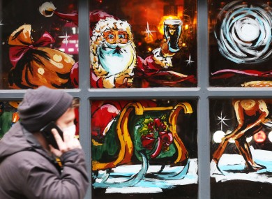 A man walks by a Christmas display in the windows of the Hairy Lemon pub in Dublin city.