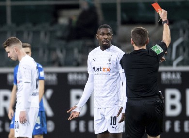 Referee Frank Willenborg shows Moenchengladbach's Marcus Thuram the red card.