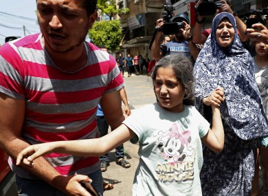 A man helps a wounded girl and a woman to an ambulance after an Israeli airstrikes at their building in Gaza City today.