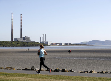 People enjoy sunny weather on Sandymount strand with by the Poolbeg chimney stacks in the background.