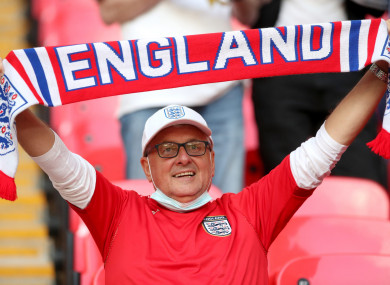 An England fan holding a scarf in the stands at Wembley Stadium.