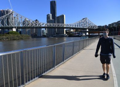 A man wearing a protective face mask is seen walking on the New Farm riverwalk, beside the Brisbane River in Brisbane
