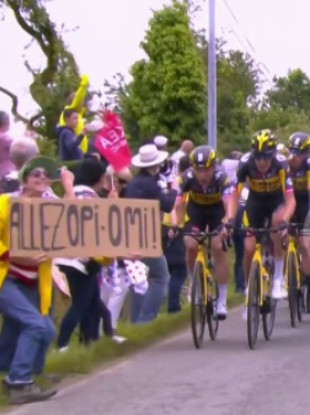 A fan holds a sign into which Tony Martin crashed, causing half of the peloton to tumble with him.