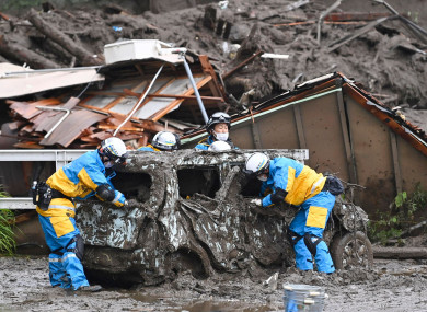 Rescuers check a damaged vehicle at the site of a mudslide in Atami, Shizuoka prefecture, southwest of Tokyo