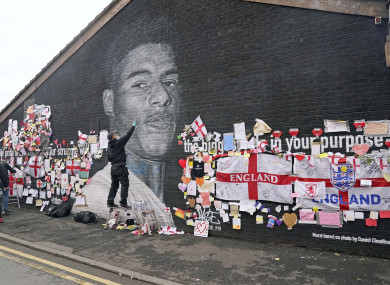 Street artist Akse repairs the mural of Manchester United striker and England player Marcus Rashford.