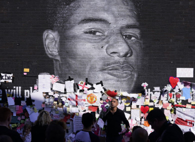 People gather to view the messages of support at the mural of Marcus Rashford