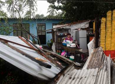 A woman clearing debris from her kitchen after a part of her home was damaged by Hurricane Grace.
