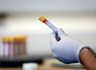 A paramedic holds a test tube containing a blood sample.