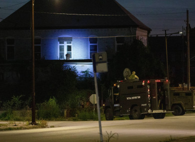 Illinois State Police in armoured trucks shine a spotlight on a building during a manhunt after a shooting in southern Illinois