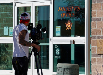A news cameraman records the entrance of the Santa Fe County Sheriff office