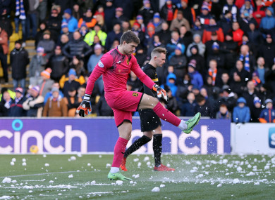 Livingston goalkeeper Max Stryjek kicks snowballs off the pitch.