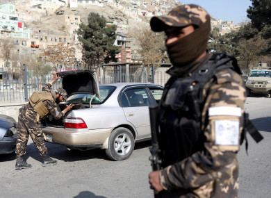 Taliban fighter searches a car as they hold a checkpoint in Kabul