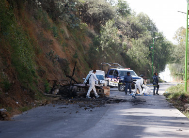 Forensic investigators work an area where a burned-out car was found after a gang rammed several vehicles into a prison and escaped with nine inmates, in Tula, Mexico