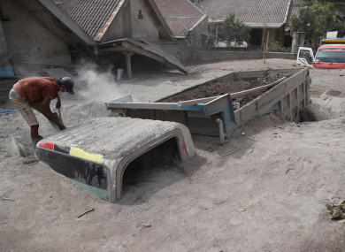 A man inspects a lorry buried in the ash following the eruption of Mount Semeru in Lumajang district, East Java province, Indonesia.