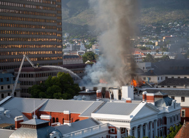 Fire crews spray water on flames erupting from a building at South Africa’s Parliament