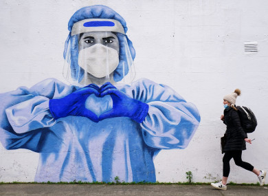 A woman passes a mural of a frontline worker in Dublin.