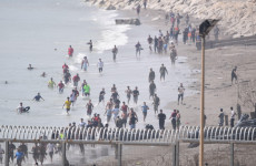 Hundreds of people swim round barriers and enter North African Spanish territory from Morocco